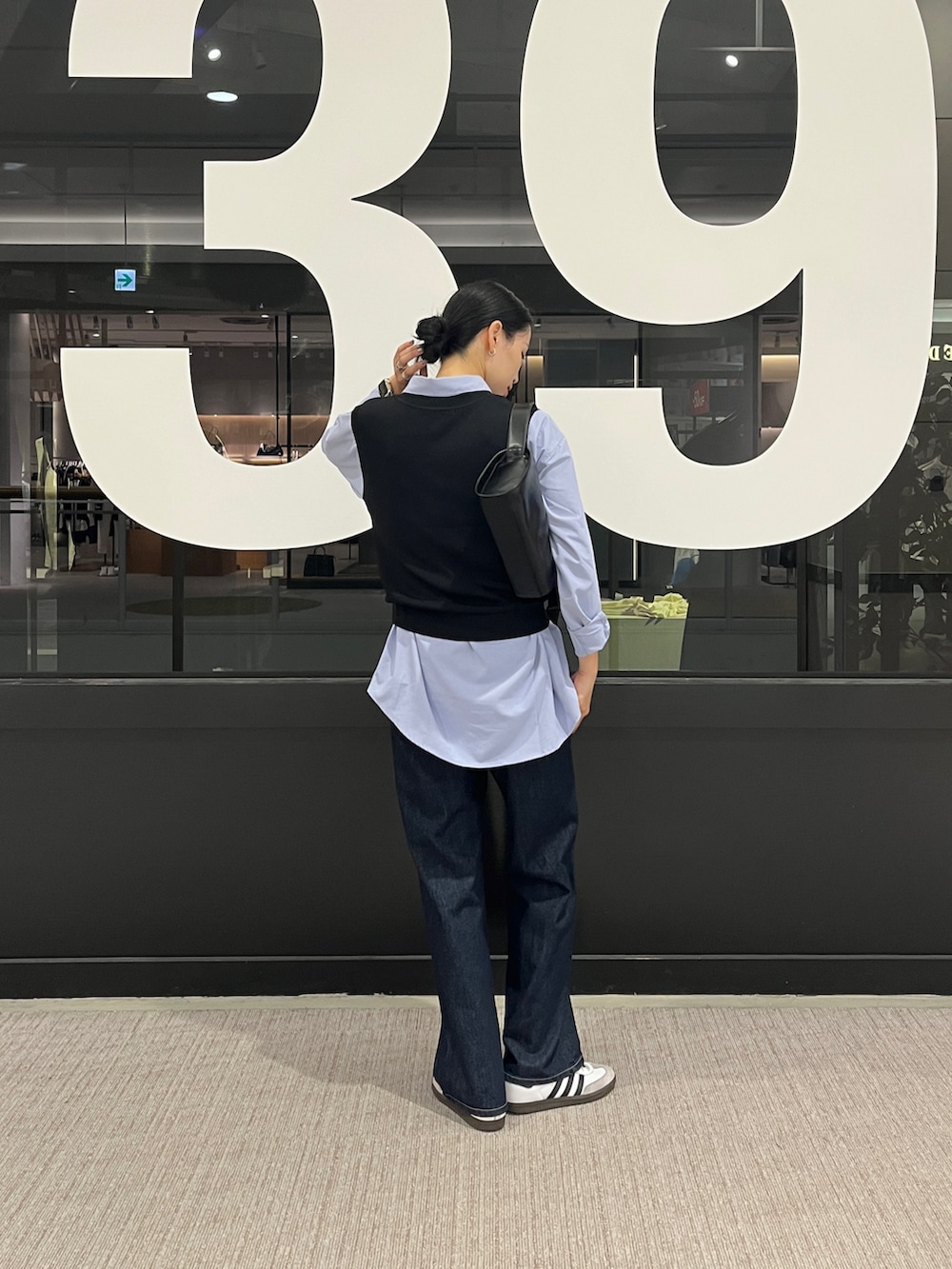 ブルー系のデニムパンツ、ブルー系のシャツ/ブラウス、ブラック系のベストを着用したレディースの秋コーディネートの4枚目の写真