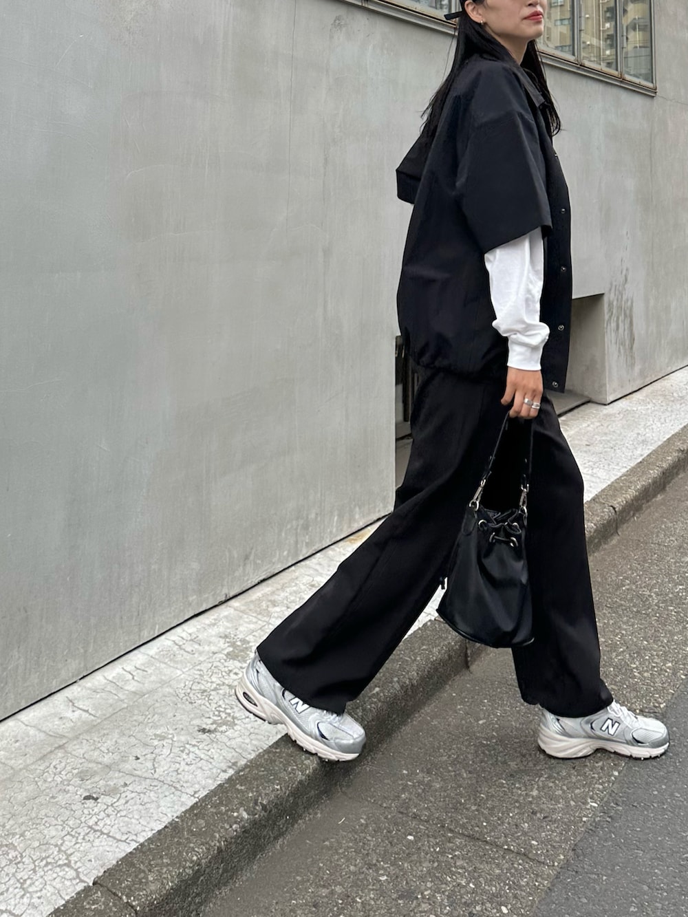 ブラック系のスラックス、ホワイト系のTシャツ/カットソー、ブラック系のシャツ/ブラウスを着用したレディースの春コーディネートの2枚目の写真