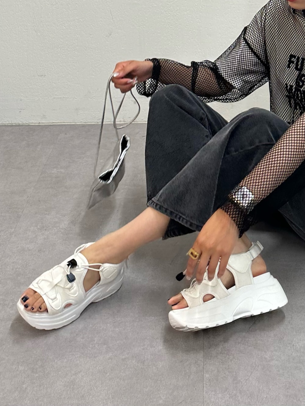 ブラック系のデニムパンツ、ホワイト系のサンダル、ホワイト系のTシャツ/カットソーを着用したレディースの春コーディネートの3枚目の写真