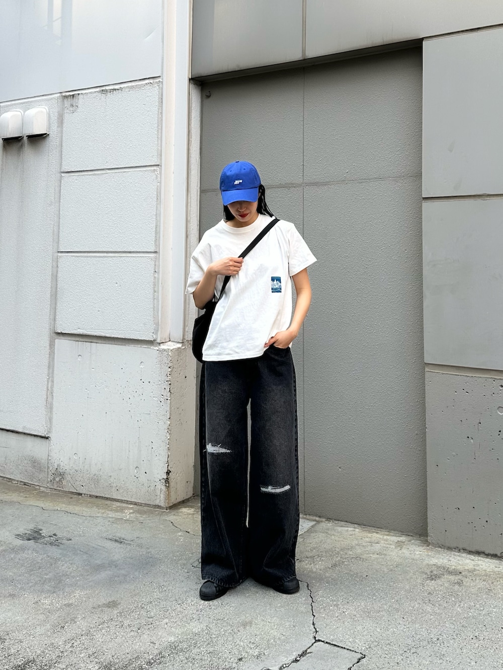 ブラック系のデニムパンツ、ホワイト系のTシャツ/カットソー、ブラック系のショルダーバッグを着用したレディースの春コーディネートの4枚目の写真