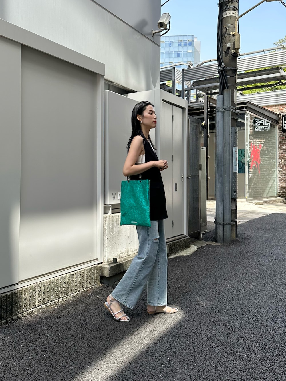 ブルー系のデニムパンツ、シルバー系のサンダル、グリーン系のトートバッグを着用したレディースの春コーディネートの3枚目の写真