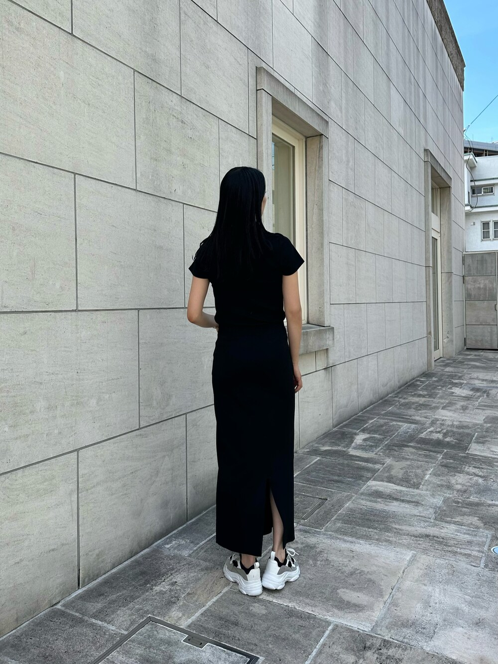 ブラック系のTシャツ/カットソー、ブラック系のスカート、ブラック系のスニーカーを着用したレディースの夏コーディネートの2枚目の写真