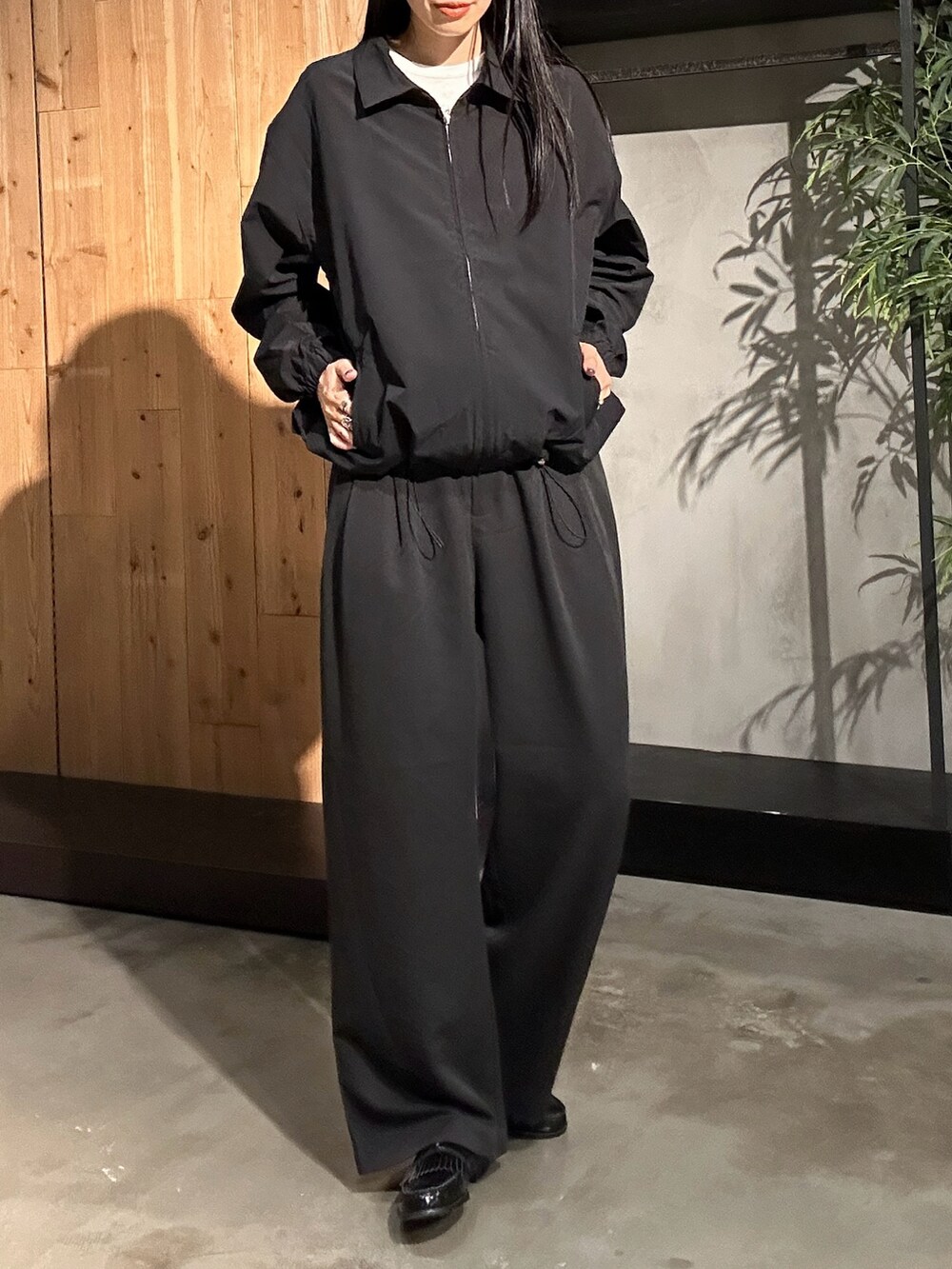 ブラック系のスラックス、ブラック系のブルゾン、ホワイト系のTシャツ/カットソーを着用したレディースの秋コーディネートの2枚目の写真