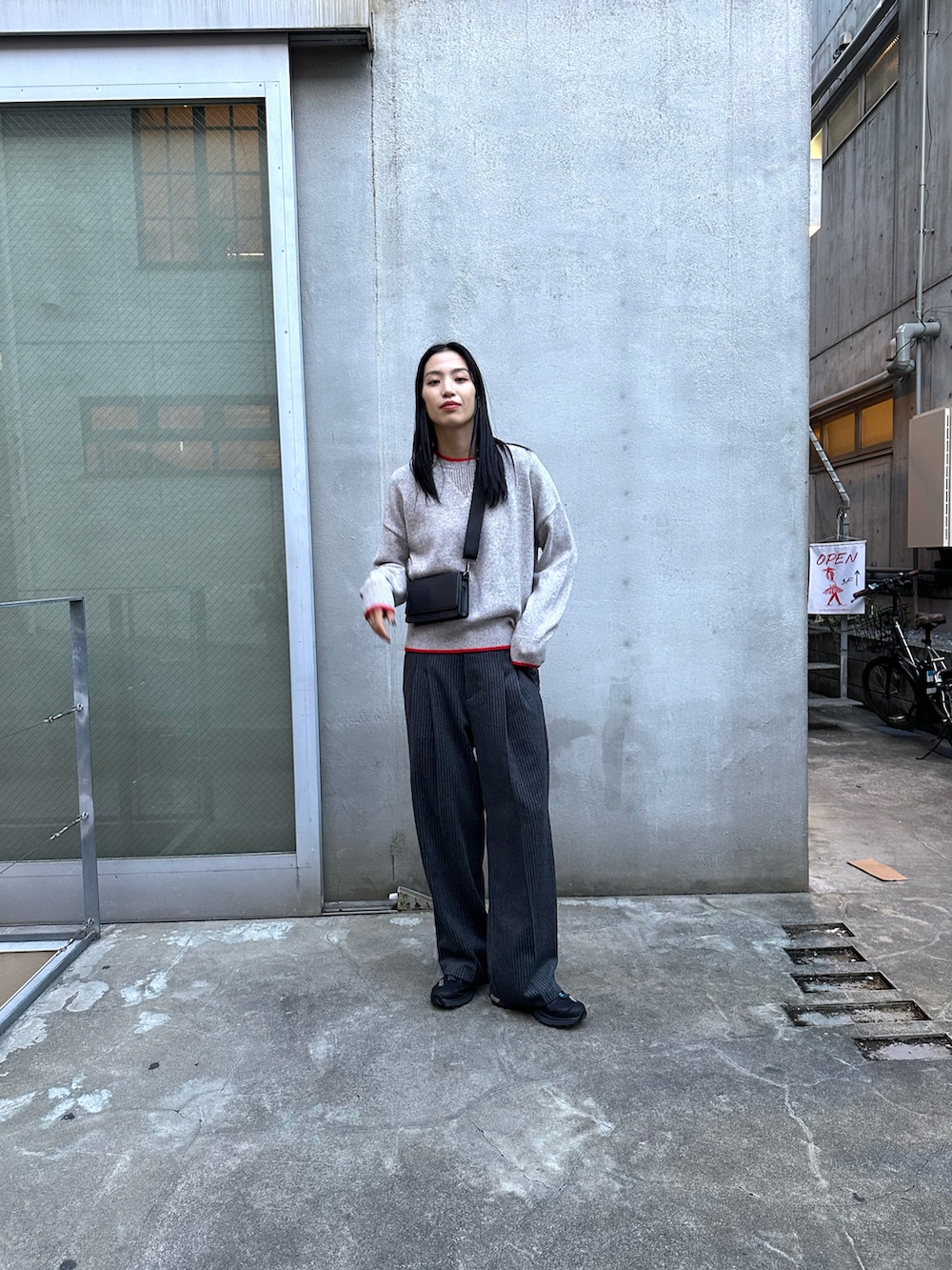 グレー系のスラックス、ブラック系のダウンジャケット/コート、グレー系のニット/セーターを着用したレディースの冬コーディネートの4枚目の写真