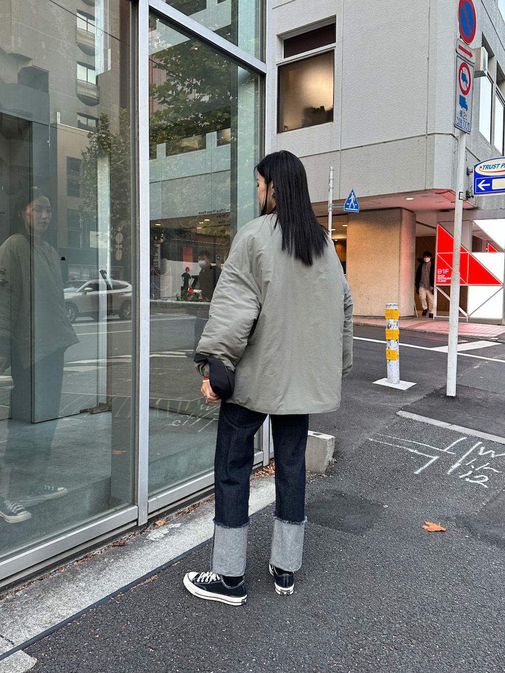 ブルー系のデニムパンツ、グリーン系のダウンジャケット/コート、オレンジ系のニット/セーターを着用したレディースの秋コーディネートの2枚目の写真