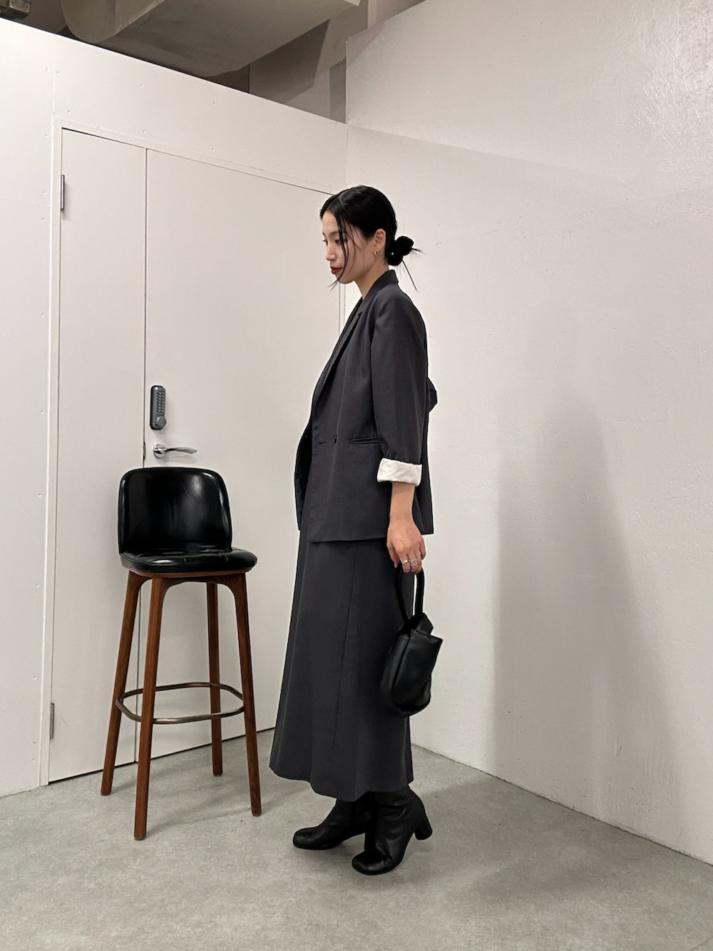 グレー系のテーラードジャケット、グレー系のドレス、ブラック系のハンドバッグを着用したレディースの冬コーディネートの2枚目の写真