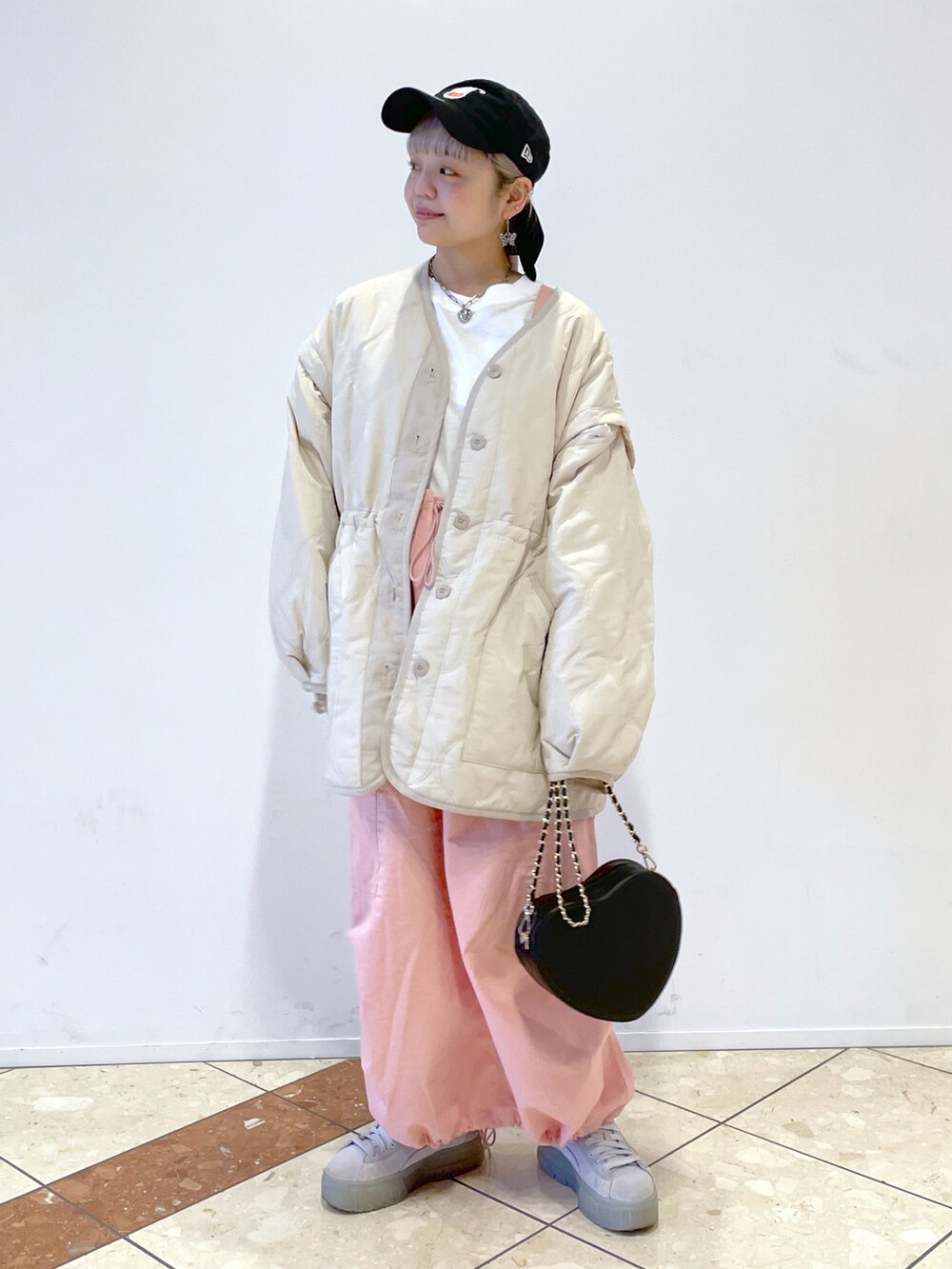 ホワイト系のミリタリージャケット、ピンク系のジャンパースカート、ブラック系のショルダーバッグを着用したレディースの秋コーディネートの2枚目の写真