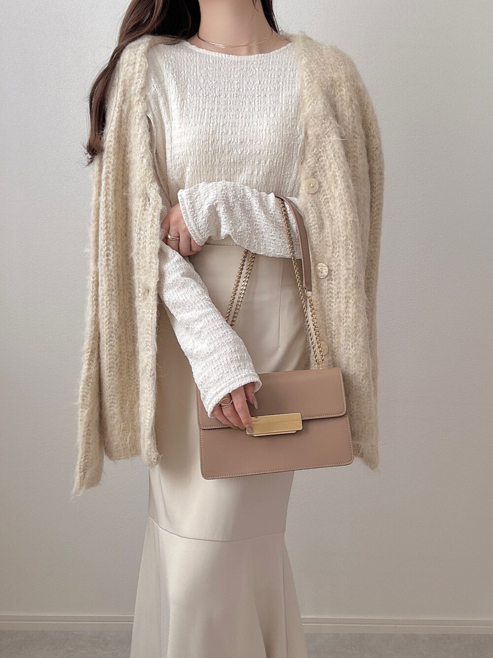 ホワイト系のスカート、ベージュ系のカーディガン/ボレロ、ホワイト系のTシャツ/カットソーを着用したレディースの冬コーディネートの2枚目の写真