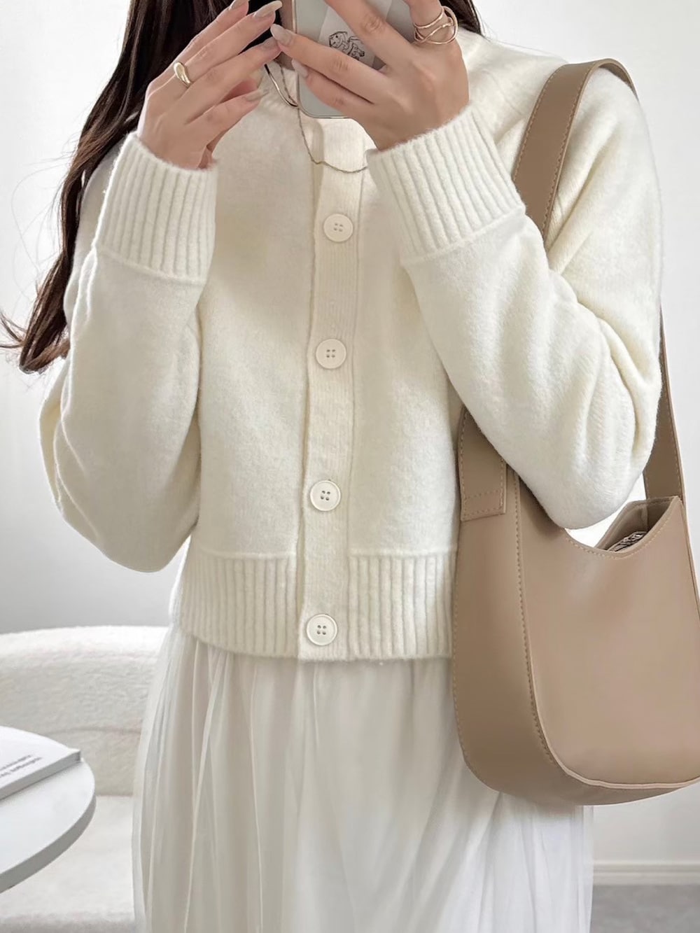 ホワイト系のカーディガン/ボレロ、ホワイト系のスカート、ブラック系のパンプスを着用したレディースの春コーディネートの2枚目の写真