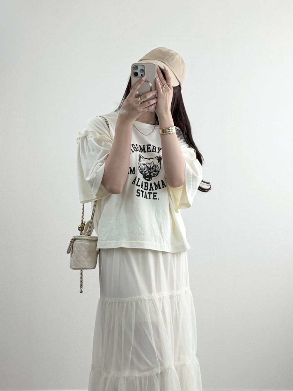 ホワイト系のスカート、ブラウン系のスニーカー、ホワイト系のショルダーバッグを着用したレディースの夏コーディネートの2枚目の写真