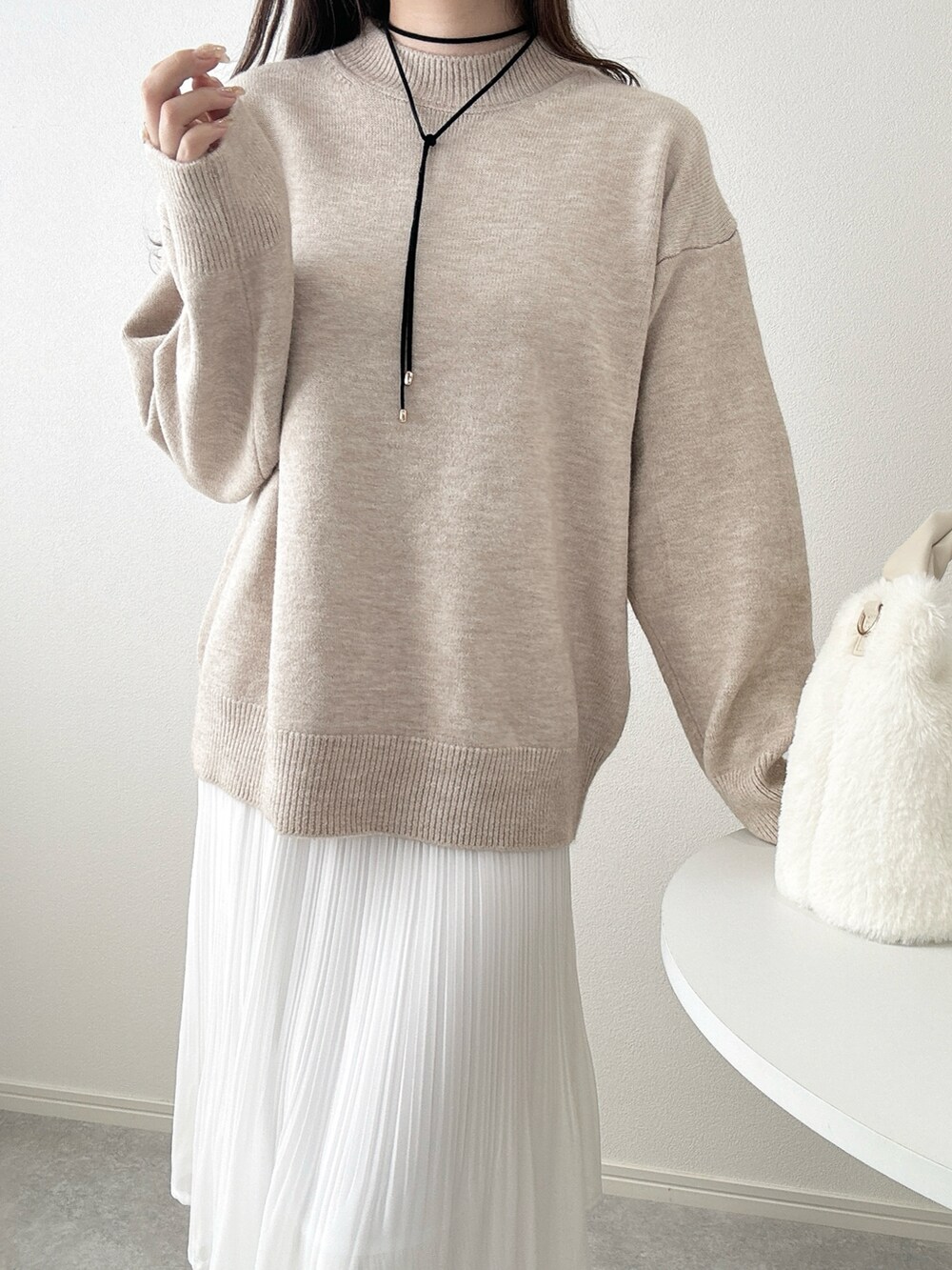 ホワイト系のスカート、ベージュ系のニット/セーターを着用したレディースの秋コーディネートの2枚目の写真