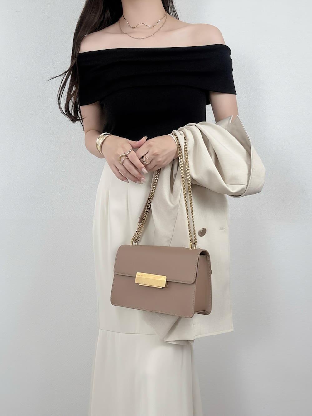 ベージュ系のテーラードジャケット、ホワイト系のスカートを着用したレディースの夏コーディネートの2枚目の写真