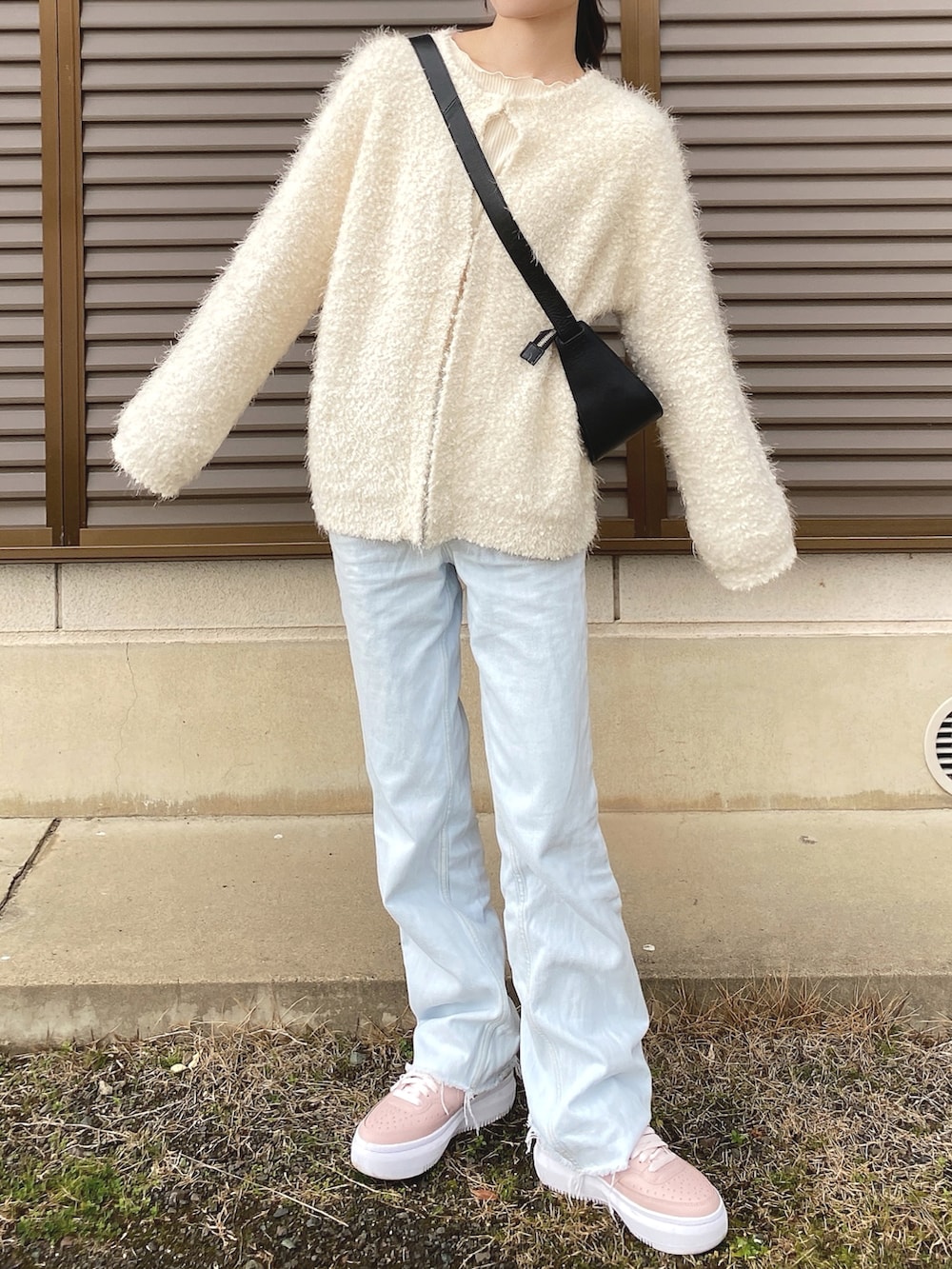 ホワイト系のカーディガン/ボレロ、ブラック系のショルダーバッグ、ブルー系のデニムパンツを着用したレディースの春コーディネートの2枚目の写真