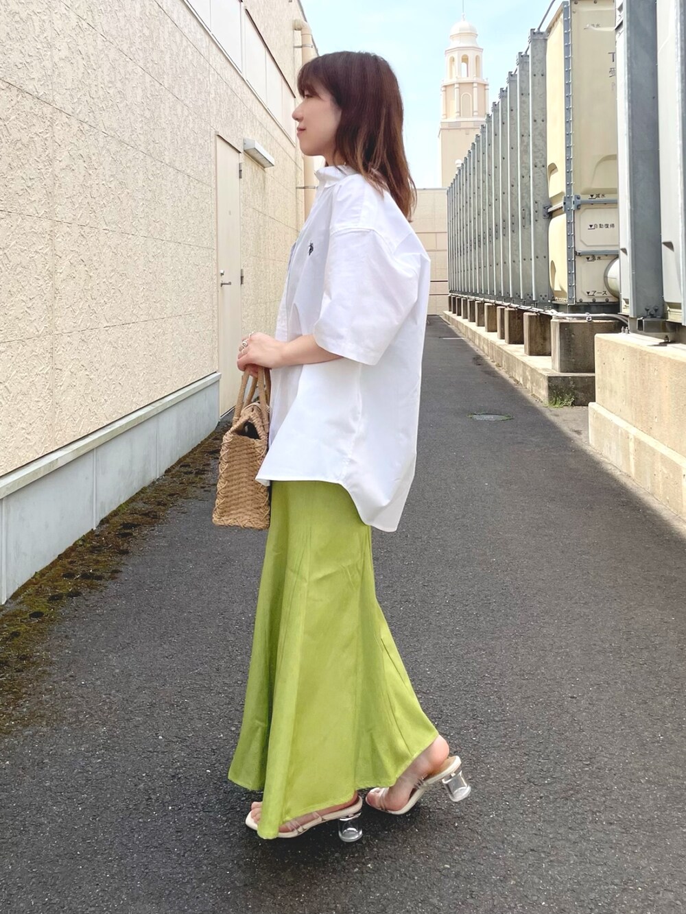 グリーン系のスカート、ベージュ系のトートバッグ、ホワイト系のサンダルを着用したレディースの春コーディネートの2枚目の写真