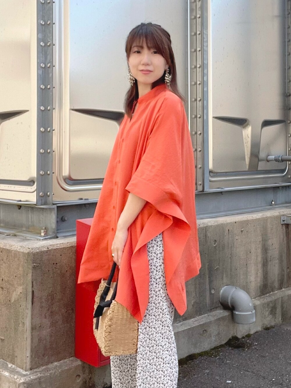 オレンジ系のシャツ/ブラウス、ブラウン系のニット/セーター、ベージュ系のボストンバッグを着用したレディースの春コーディネートの2枚目の写真
