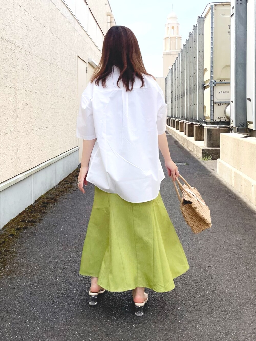グリーン系のスカート、ベージュ系のトートバッグ、ホワイト系のサンダルを着用したレディースの春コーディネートの3枚目の写真
