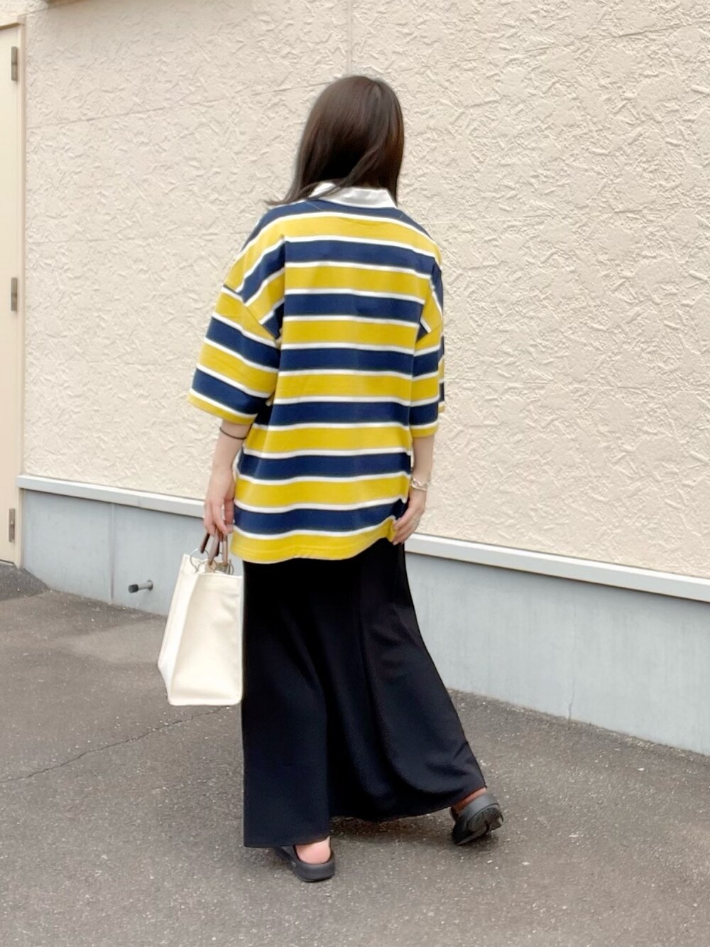 イエロー系のシャツ/ブラウス、ブラック系のスカート、ホワイト系のトートバッグを着用したレディースの春コーディネートの4枚目の写真