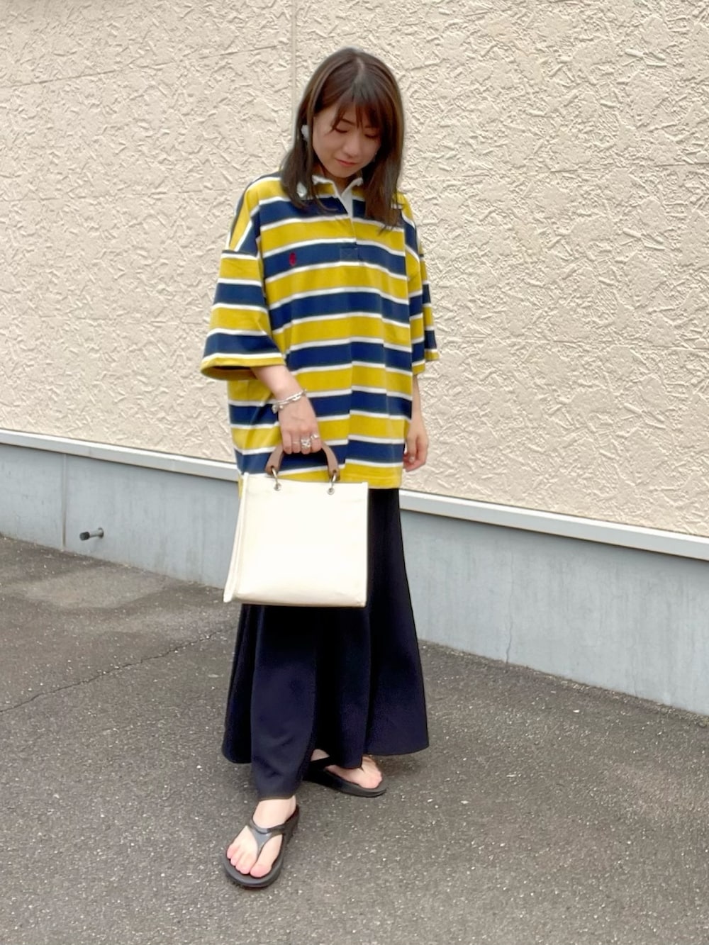 イエロー系のシャツ/ブラウス、ブラック系のスカート、ホワイト系のトートバッグを着用したレディースの春コーディネートの2枚目の写真