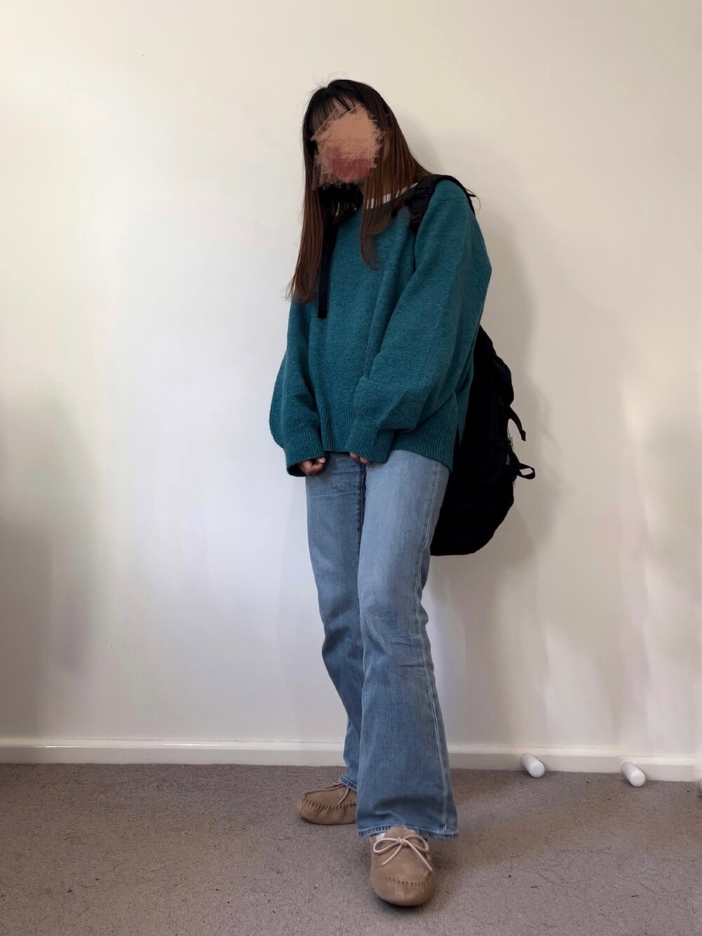 グリーン系のニット/セーター、ブラック系のバックパック/リュック、ブルー系のデニムパンツを着用したレディースの秋コーディネートの2枚目の写真