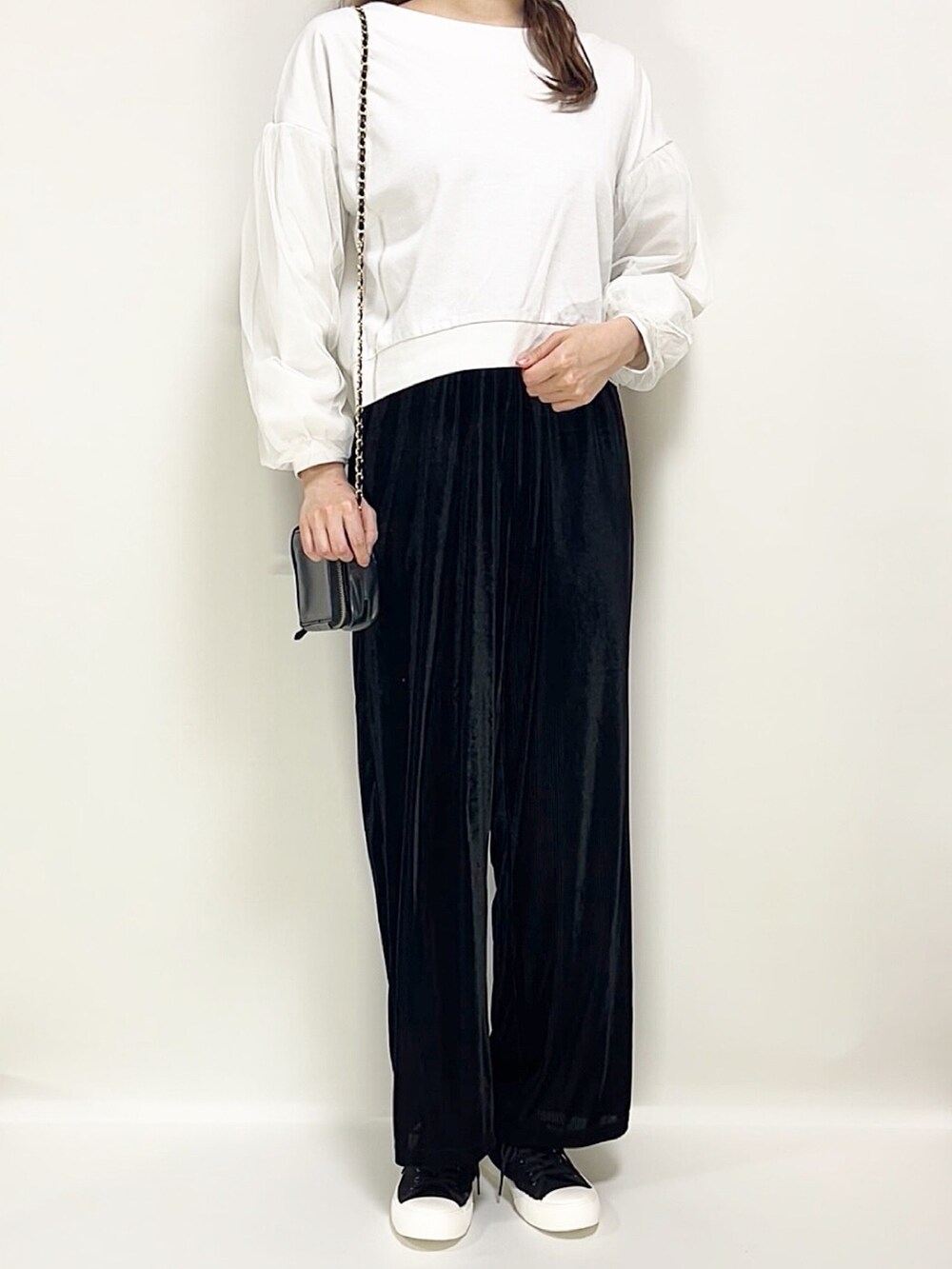 ホワイト系のトップス、ブラック系のパンツ、ブラック系のスニーカーを着用したレディースの春コーディネートの2枚目の写真