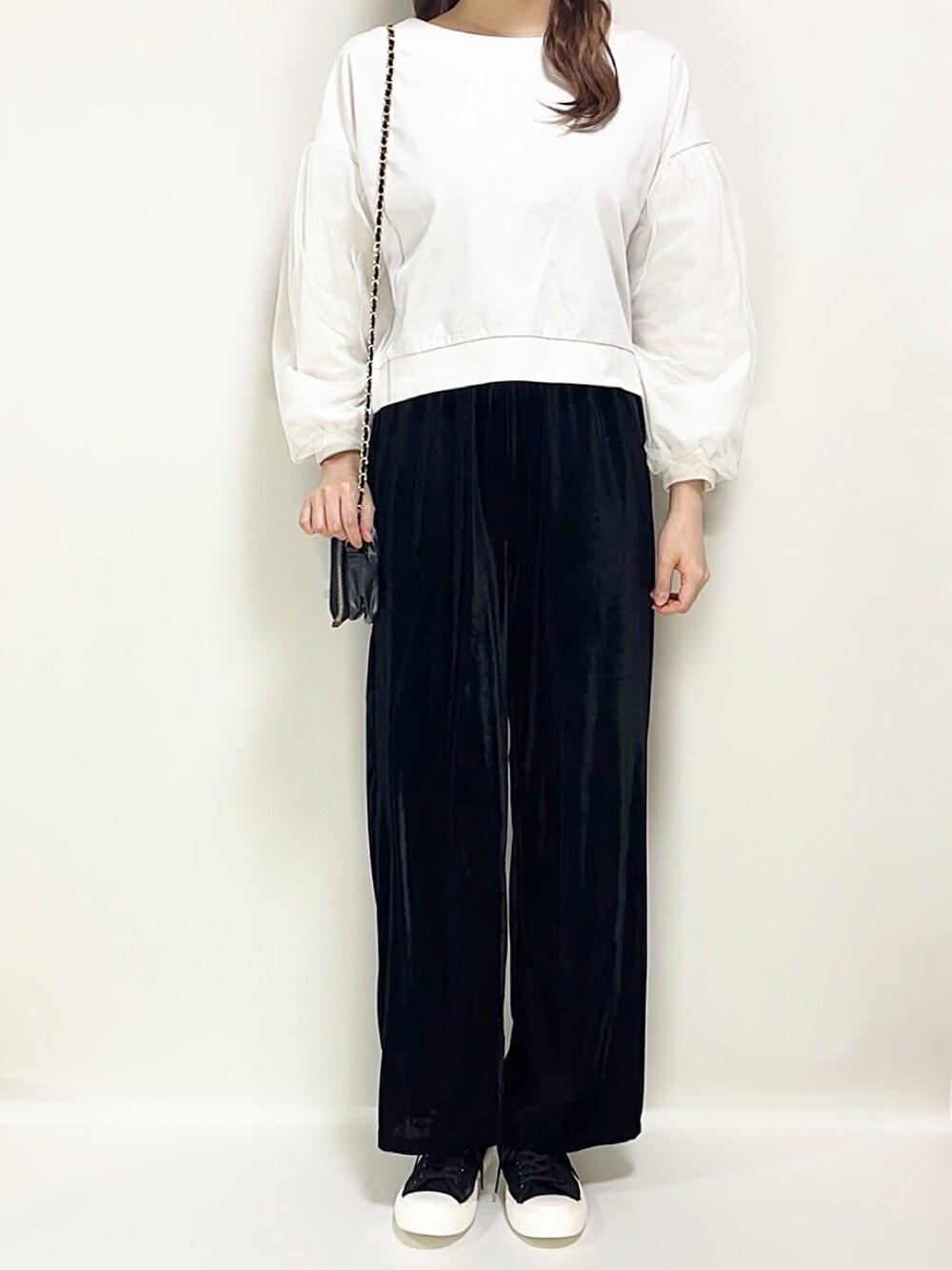ホワイト系のトップス、ブラック系のパンツ、ブラック系のスニーカーを着用したレディースの春コーディネートの3枚目の写真