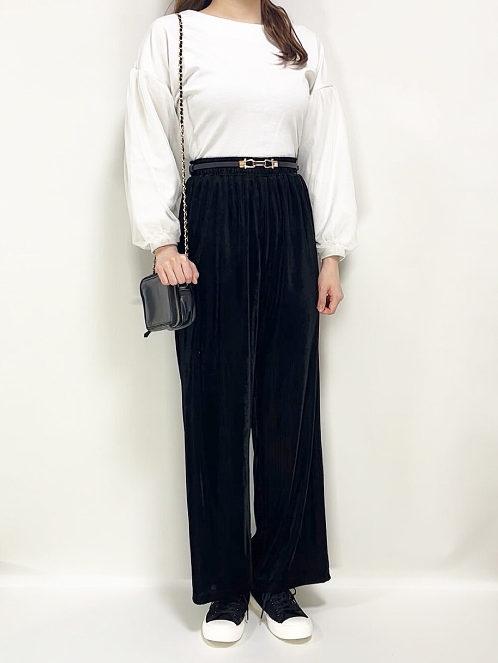 ホワイト系のトップス、ブラック系のパンツ、ブラック系のスニーカーを着用したレディースの春コーディネートの4枚目の写真