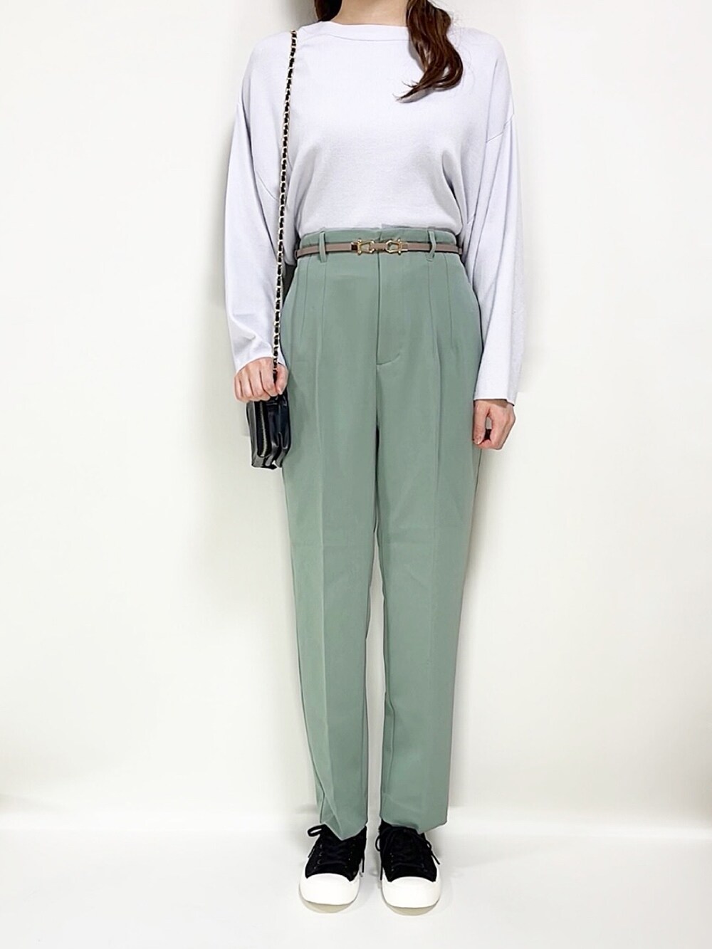 グリーン系のパンツ、ブルー系のニット/セーター、ブラック系のスニーカーを着用したレディースの春コーディネートの2枚目の写真