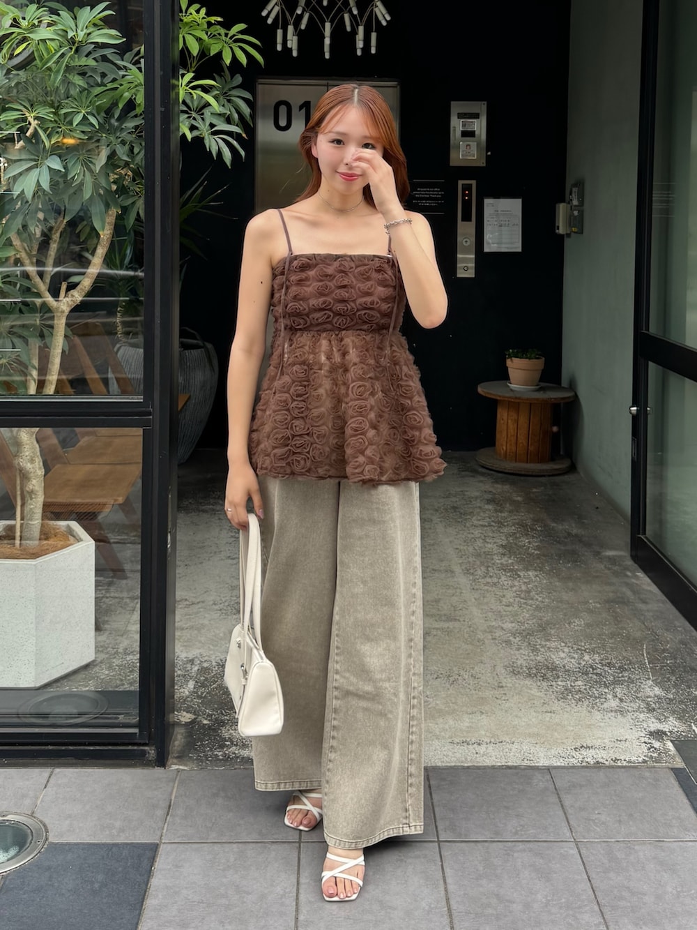 ブラウン系のシャツ/ブラウス、ホワイト系のボストンバッグ、ブラウン系のデニムパンツを着用したレディースの夏コーディネートの3枚目の写真