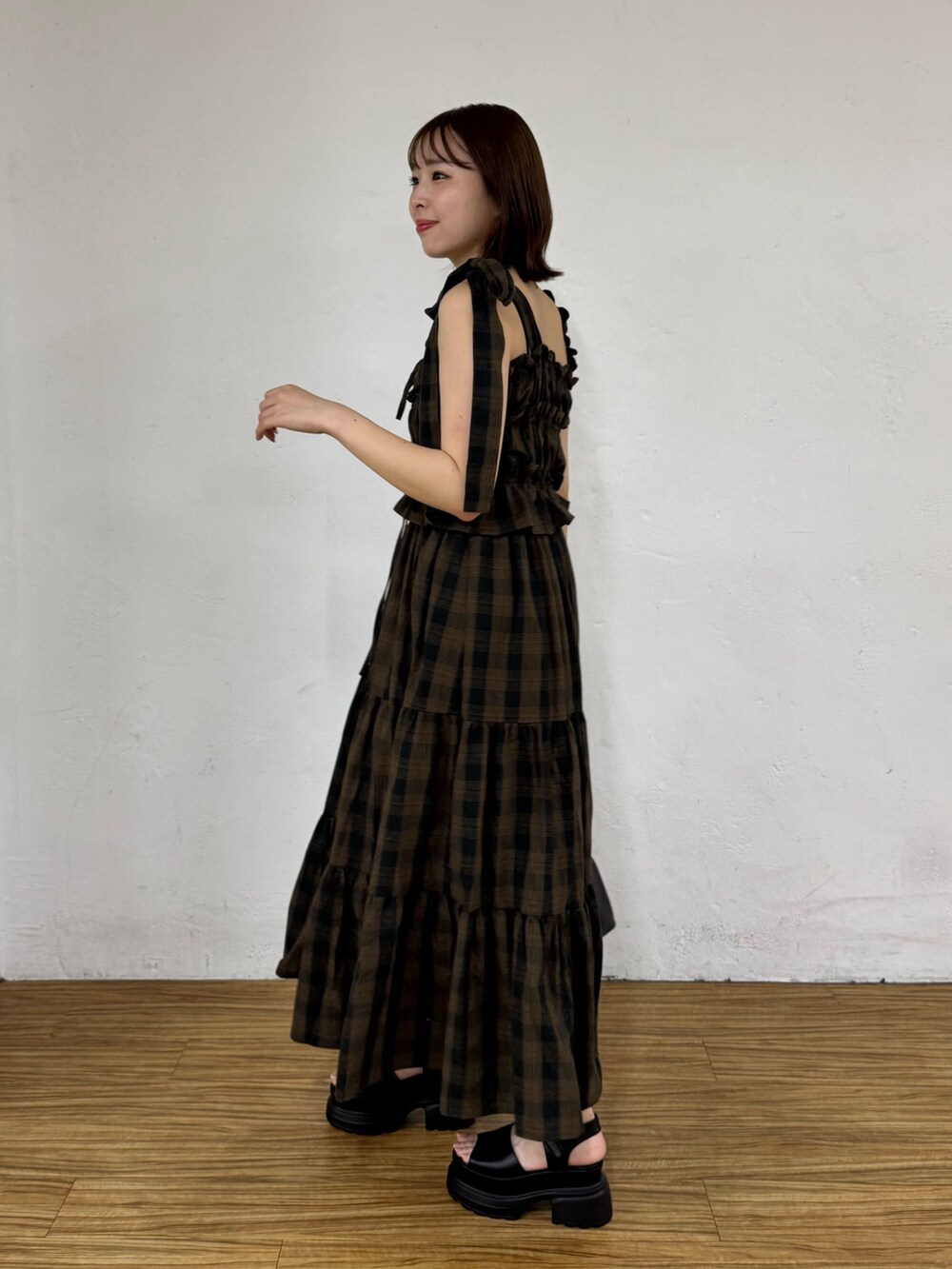 ブラウン系のワンピース、ブラック系のボストンバッグ、ブラック系のサンダルを着用したレディースの夏コーディネートの3枚目の写真