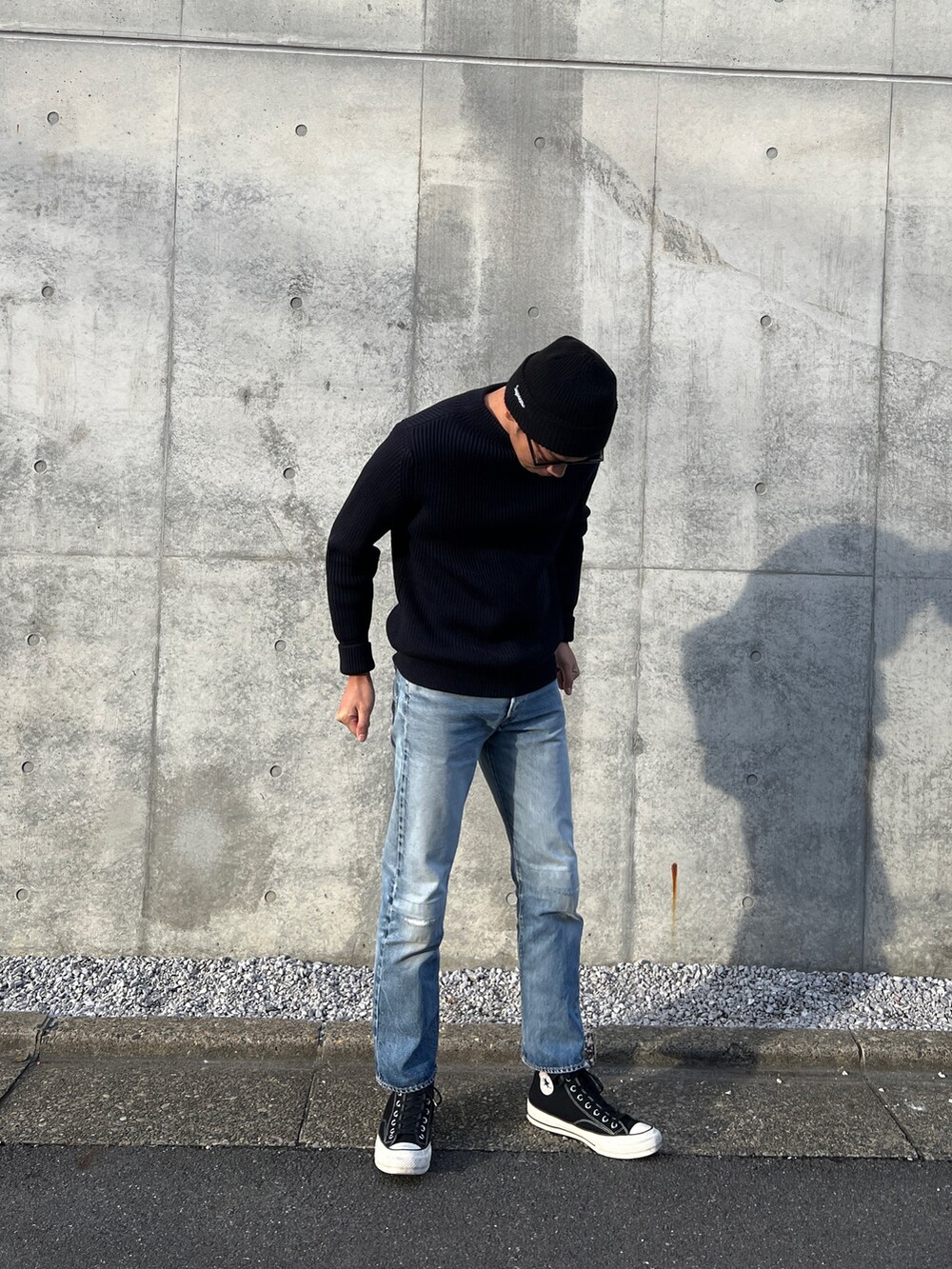 ブルー系のニット/セーター、ブルー系のデニムパンツ、ブラック系のスニーカーを着用したメンズの春コーディネートの2枚目の写真