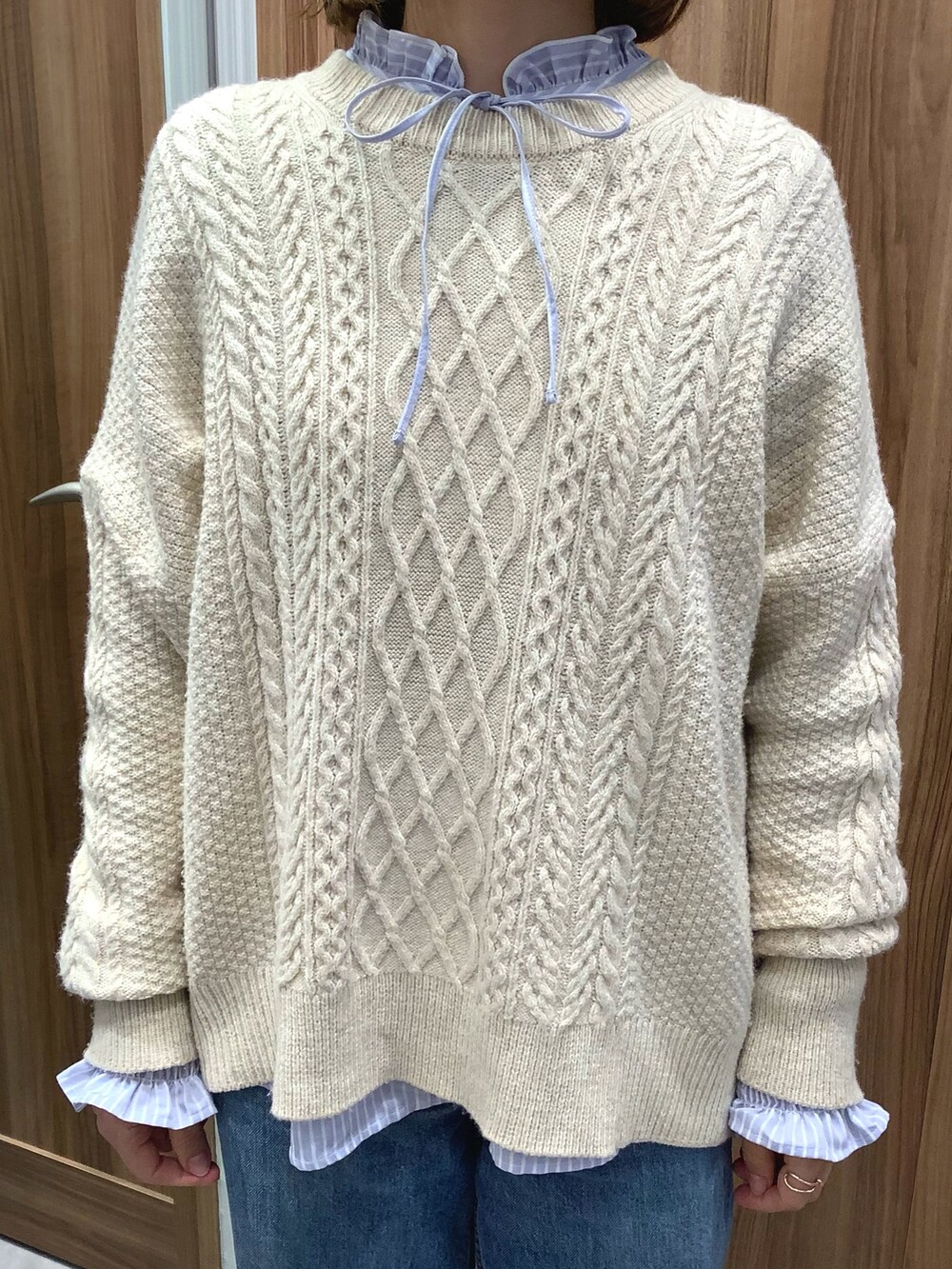 ブルー系のシャツ/ブラウス、ベージュ系のニット/セーター、ホワイト系のスニーカーを着用したレディースの冬コーディネートの4枚目の写真