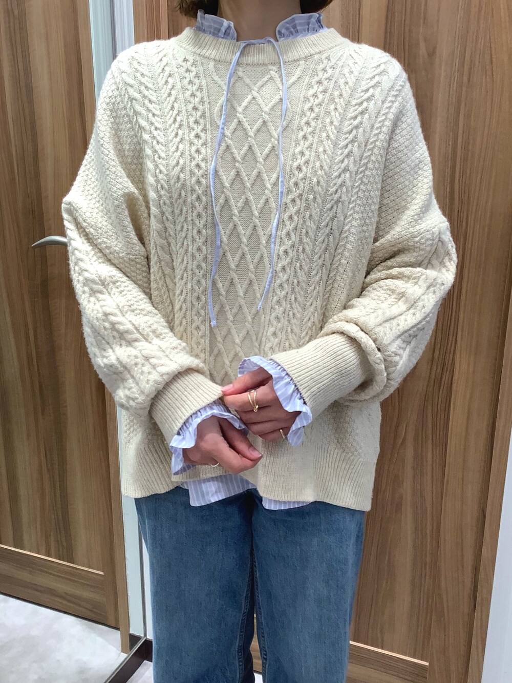 ブルー系のシャツ/ブラウス、ベージュ系のニット/セーター、ホワイト系のスニーカーを着用したレディースの冬コーディネートの3枚目の写真