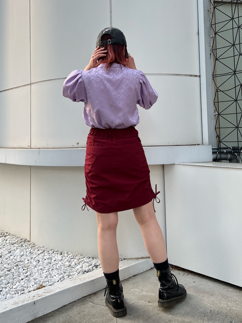 パープル系のシャツ/ブラウス、レッド系のスカート、ブラック系のキャップを着用したレディースの春コーディネートの5枚目の写真