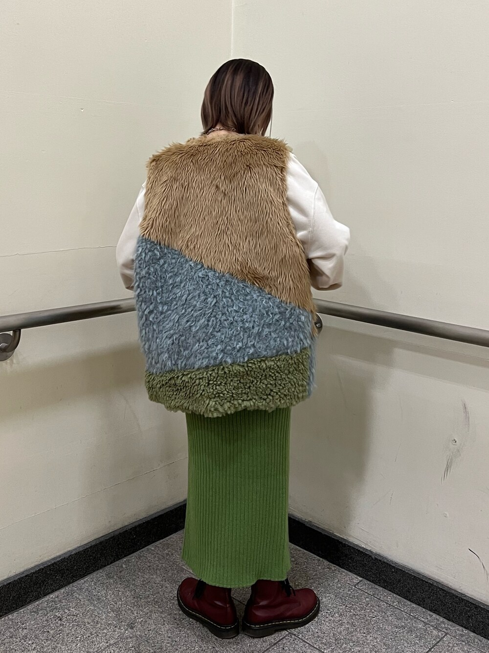 その他のベスト、ホワイト系のニット/セーター、グリーン系のスカートを着用したレディースの冬コーディネートの3枚目の写真