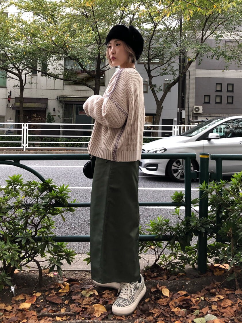 ブラック系のショルダーバッグ、ベージュ系のワンピース、ホワイト系のカーディガン/ボレロを着用したレディースの秋コーディネートの2枚目の写真