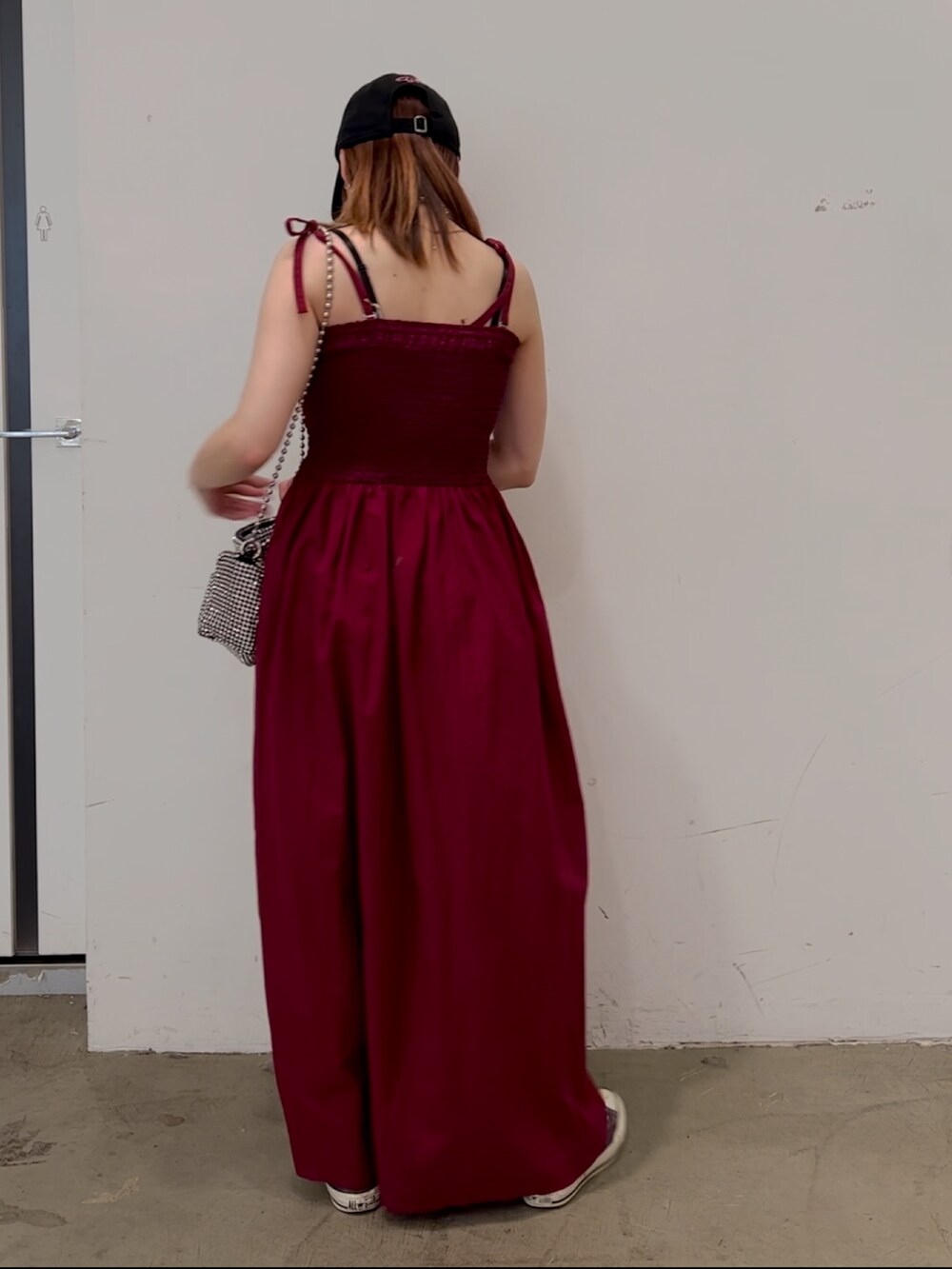 レッド系のワンピース、ホワイト系のショルダーバッグ、パープル系のスニーカーを着用したレディースの夏コーディネートの2枚目の写真