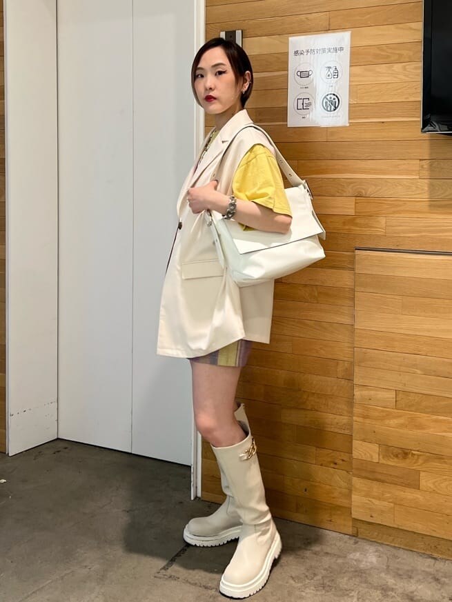 ホワイト系のブーツ、ホワイト系のベスト、ホワイト系のハンドバッグを着用したレディースの春コーディネートの4枚目の写真