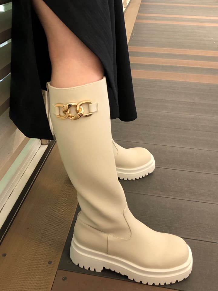 ホワイト系のシャツ/ブラウス、ブラック系のジャンパースカート、ホワイト系のブーツを着用したレディースの春コーディネートの8枚目の写真