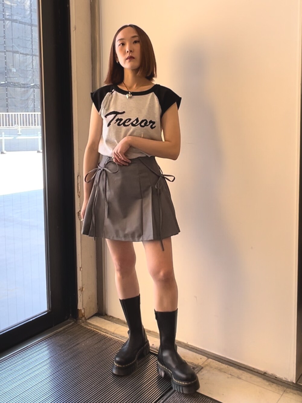 ブラック系のブーツ、オレンジ系のシャツ/ブラウス、ホワイト系のニット/セーターを着用したレディースの春コーディネートの6枚目の写真