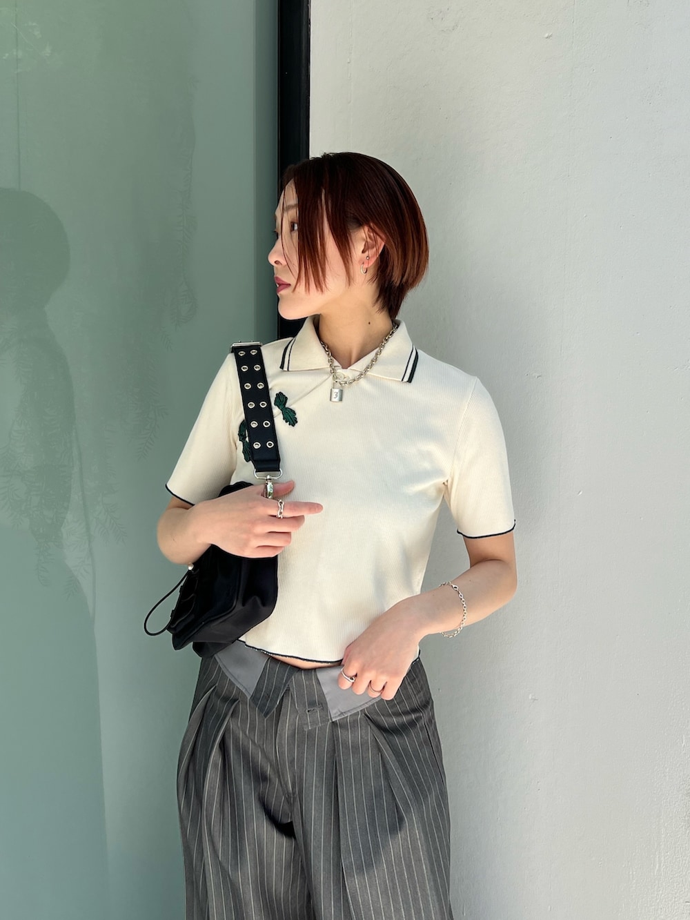 ホワイト系のポロシャツ、グレー系のスラックス、ブラック系のショルダーバッグを着用したレディースの夏コーディネートの4枚目の写真