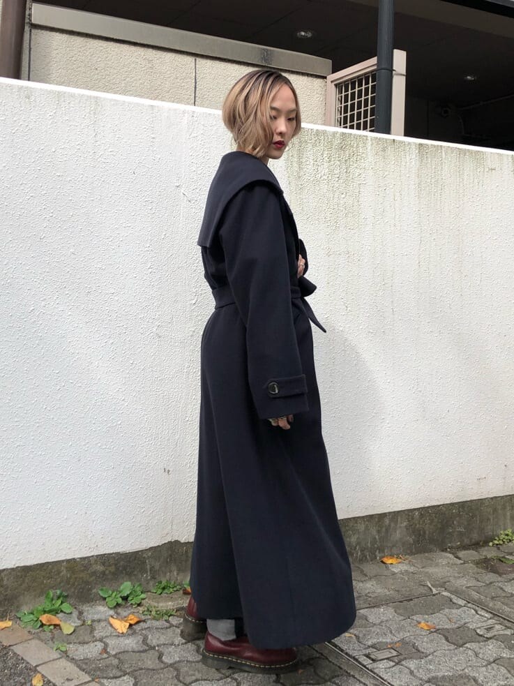 ブルー系のチェスターコート、ブラック系のデニムパンツ、ブラック系のニット/セーターを着用したレディースの秋コーディネートの5枚目の写真