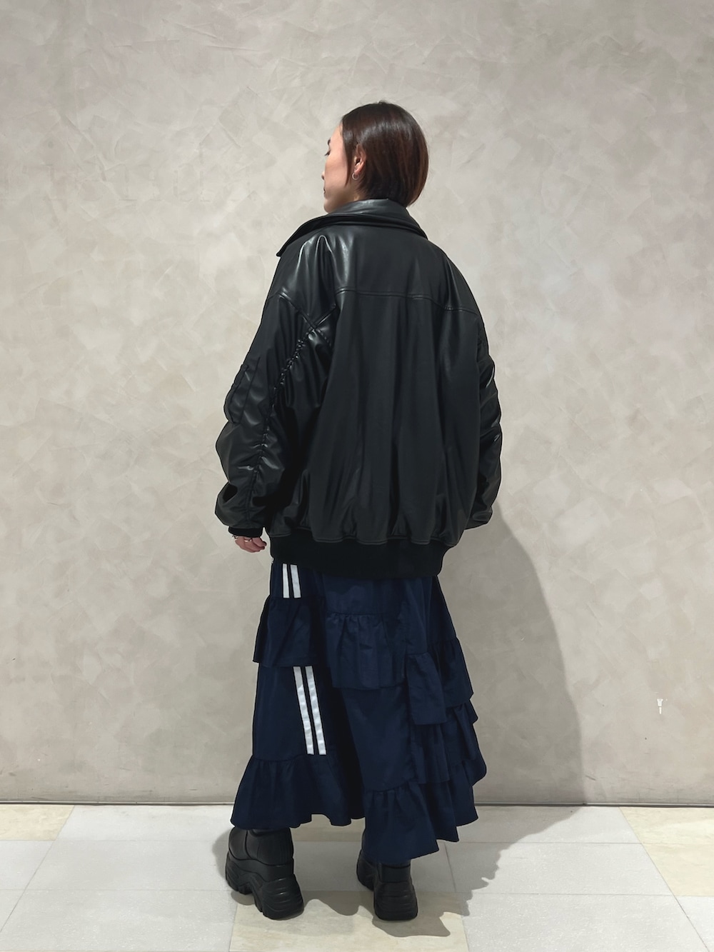 ブラック系のブルゾン、ブルー系のスカート、ブラック系のブーツを着用したレディースの秋コーディネートの2枚目の写真