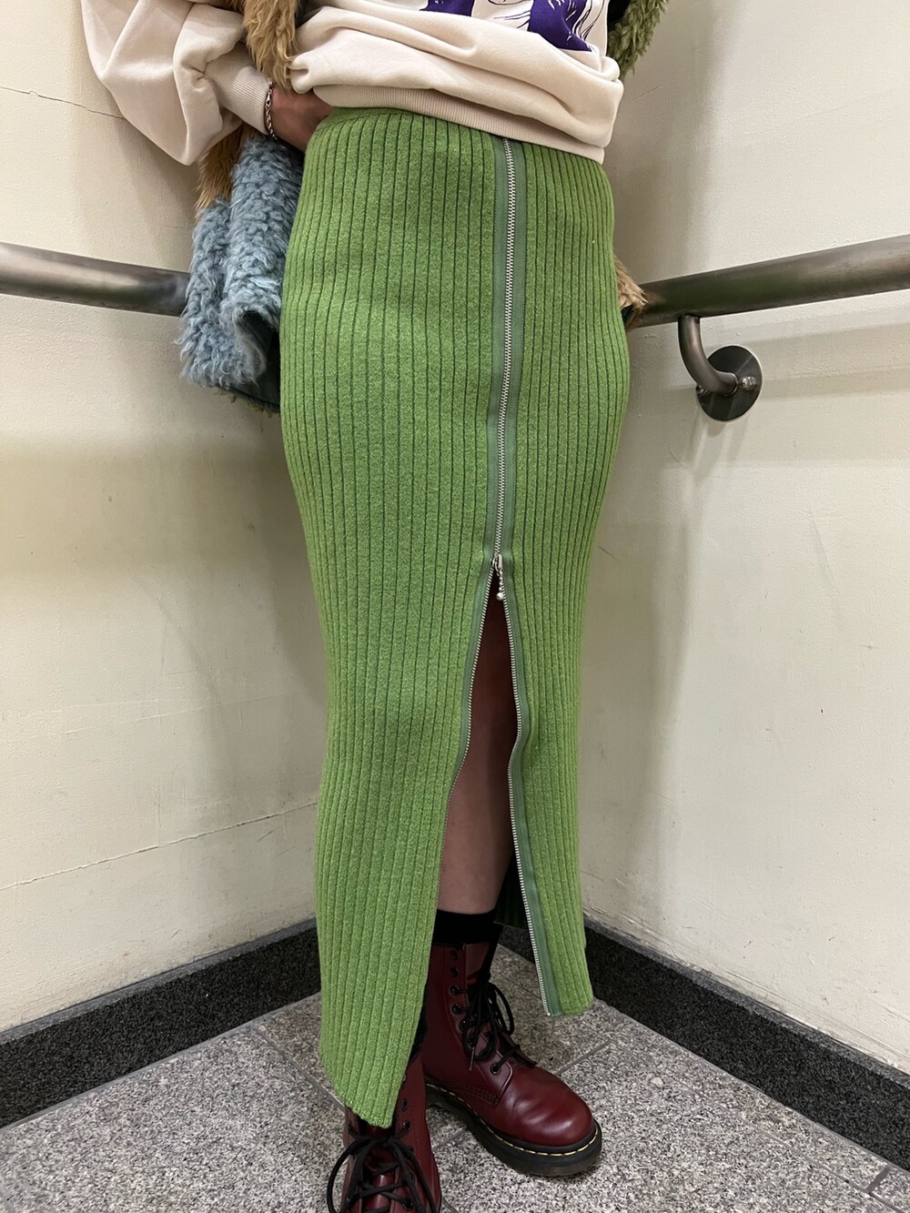 グリーン系のスカート、ホワイト系のニット/セーターを着用したレディースの冬コーディネートの6枚目の写真