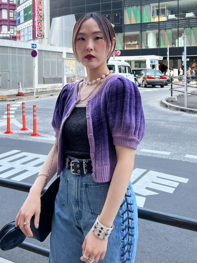 ブラック系のハンドバッグ、ブラック系のニット/セーター、ブルー系のデニムパンツを着用したレディースの夏コーディネートの5枚目の写真