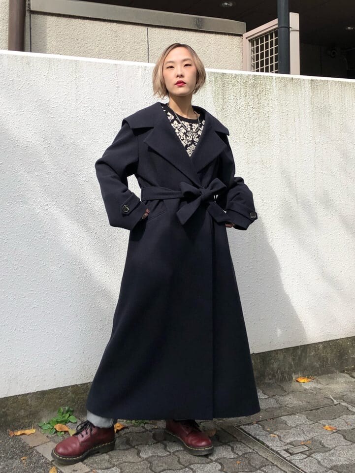 ブルー系のチェスターコート、ブラック系のデニムパンツ、ブラック系のニット/セーターを着用したレディースの秋コーディネートの4枚目の写真