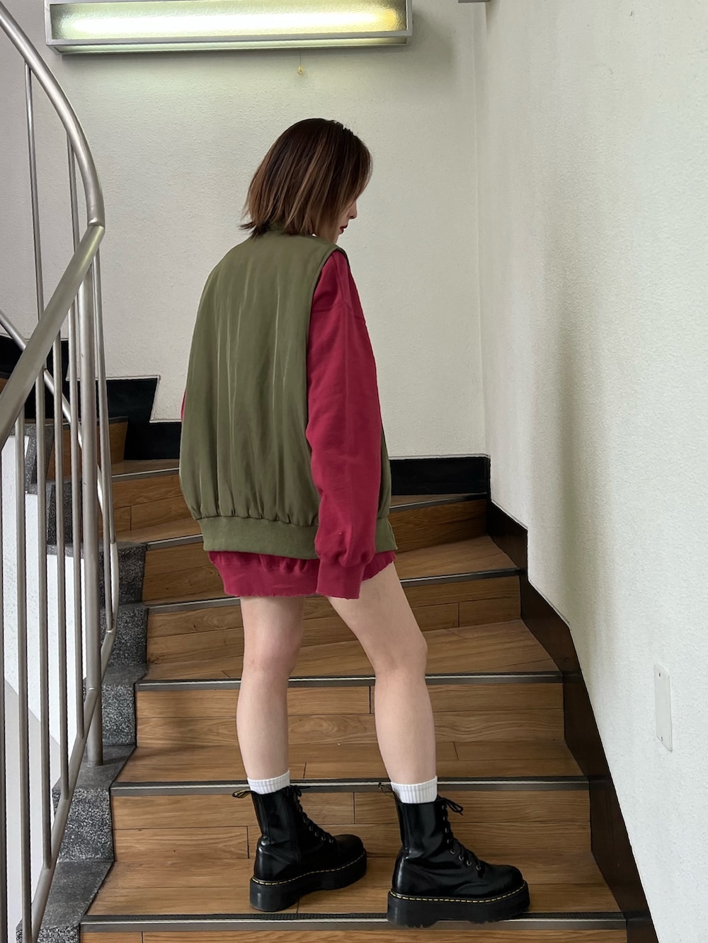 レッド系のスウェット、グリーン系のMA-1、ブラック系のデニムパンツを着用したレディースの冬コーディネートの2枚目の写真