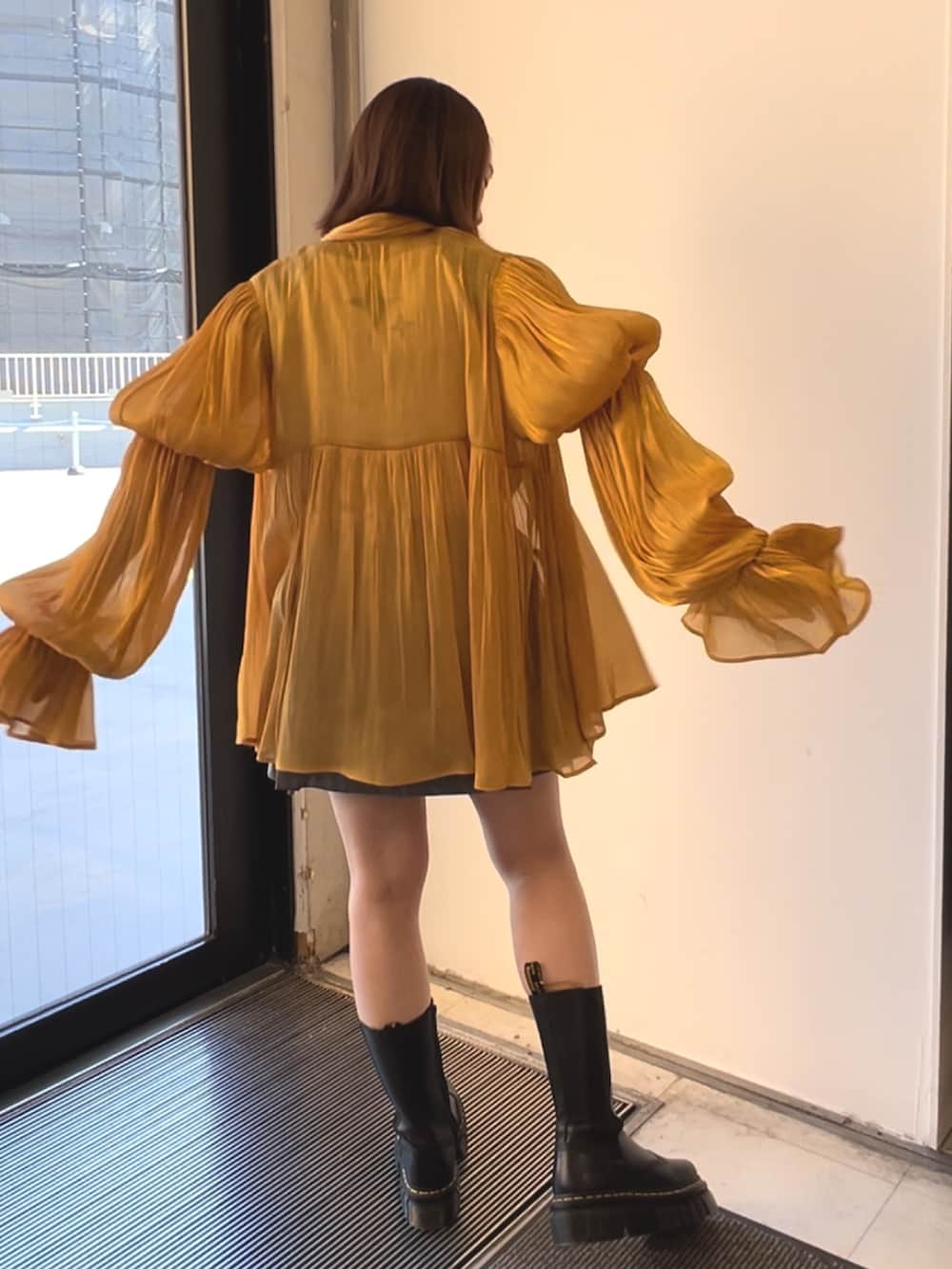 ブラック系のブーツ、オレンジ系のシャツ/ブラウス、ホワイト系のニット/セーターを着用したレディースの春コーディネートの4枚目の写真