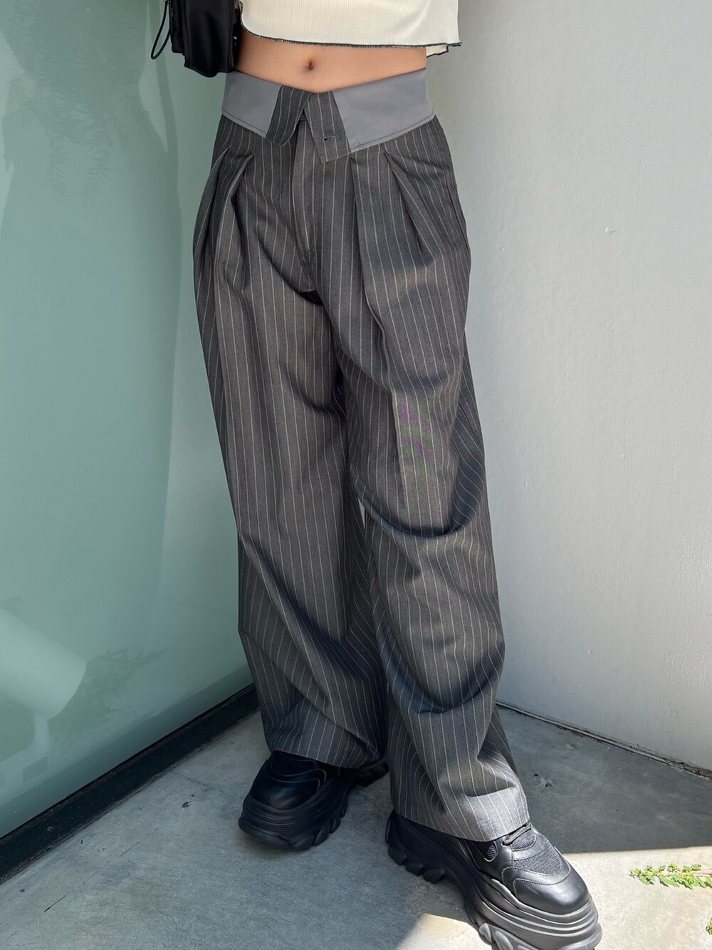 ホワイト系のポロシャツ、グレー系のスラックス、ブラック系のショルダーバッグを着用したレディースの夏コーディネートの7枚目の写真