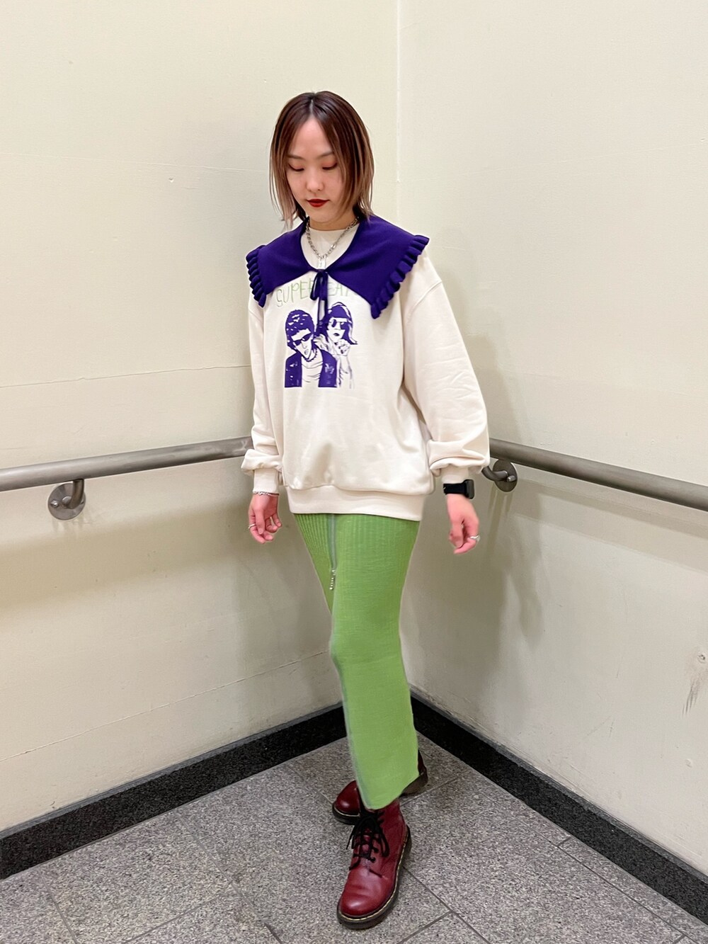 グリーン系のスカート、ホワイト系のニット/セーターを着用したレディースの冬コーディネートの2枚目の写真