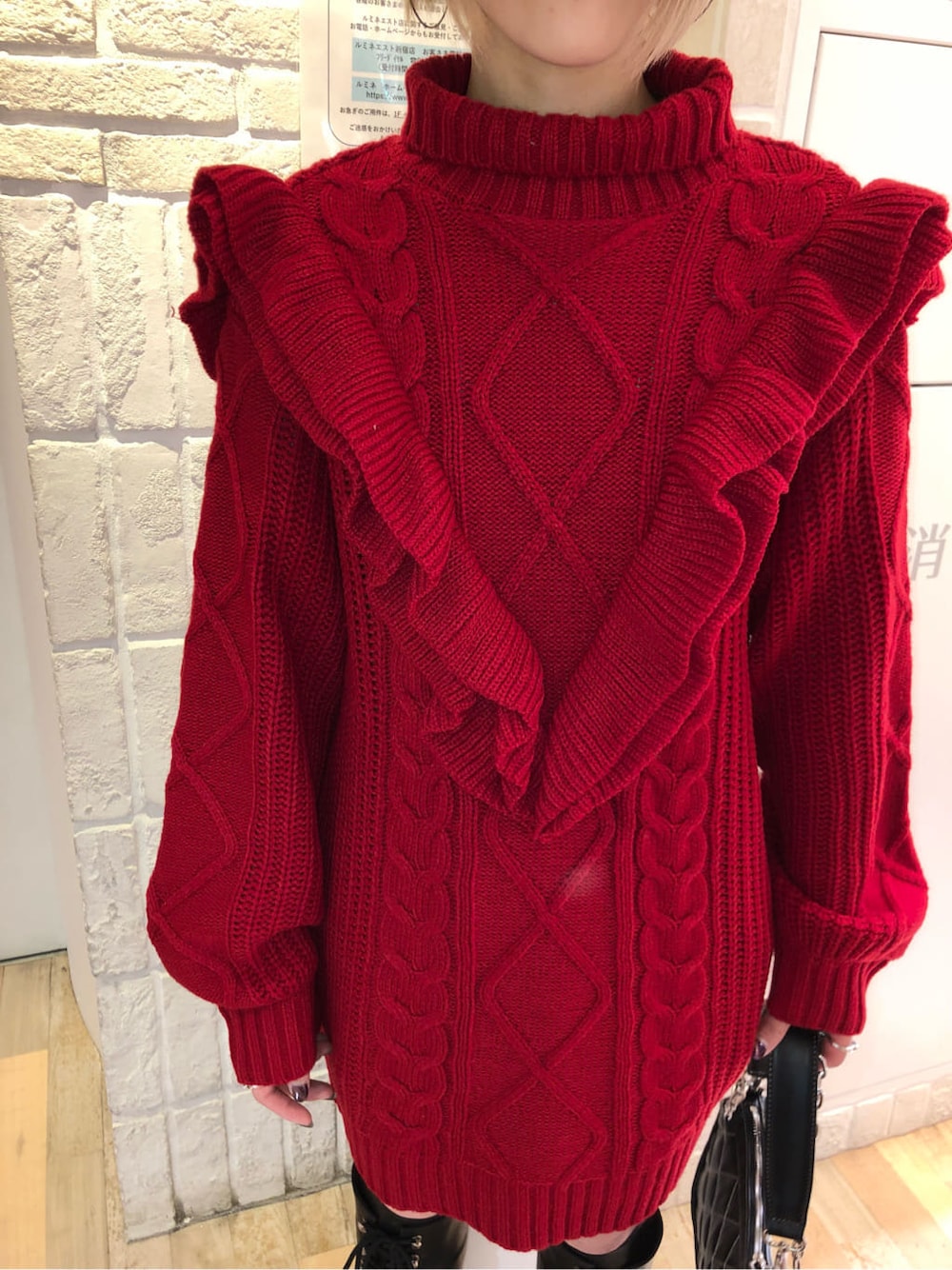 ブラック系のチェスターコート、レッド系のニット/セーター、ブラック系のブーツを着用したレディースの冬コーディネートの8枚目の写真